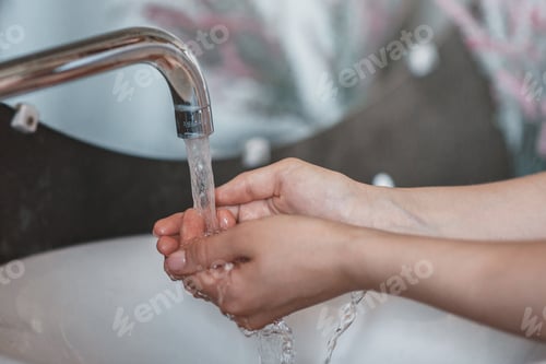 Preview: Unrecognizable young woman washing hands in sink at bathroom, closeup of hands