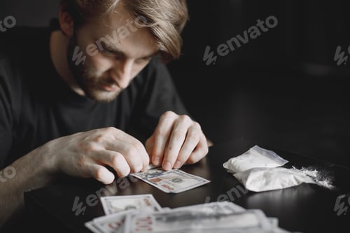 Preview: Young addicted man taking cocaine with dollar
