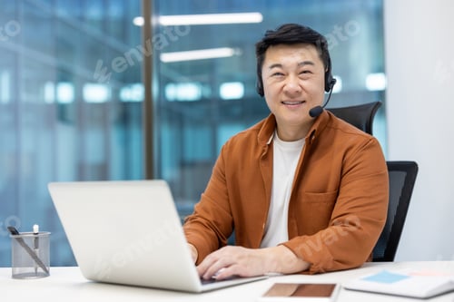 Preview: Asian man mature businessman working with a laptop wearing a headset at office