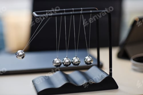 Preview: Newton Cradle Demonstrating Physics Principles in Modern Office Setting