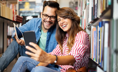 Preview: Happy young student couple taking a selfie in school library