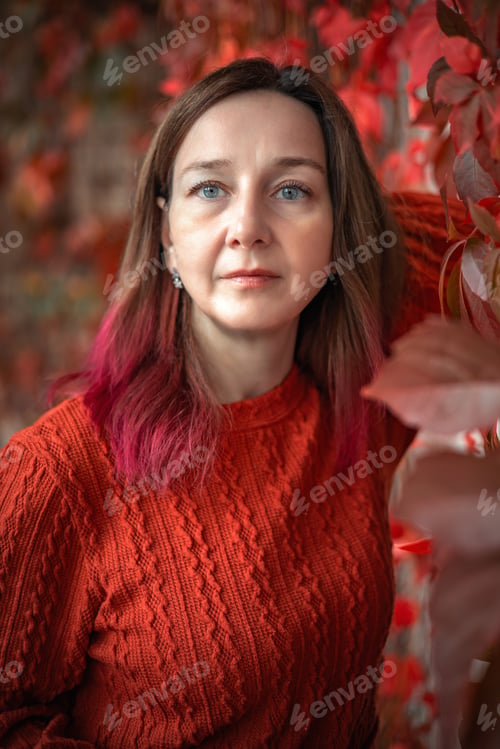 Preview: A woman in a terracotta dress against a background of red and yellow autumn grape leaves. Autumn