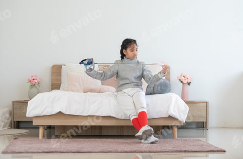 Preview: A girl in fencing gear is sitting and rest on the bed