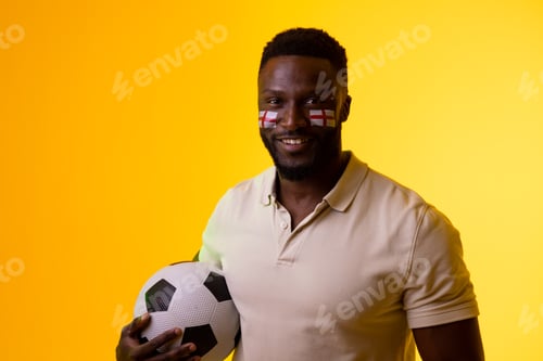 Preview: Image of happy african american male soccer fan with flag of england in yellow lighting