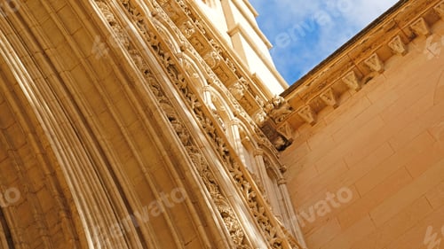 Preview: Gothic church portal close-up with richly carved stone arches and statue, upward view.