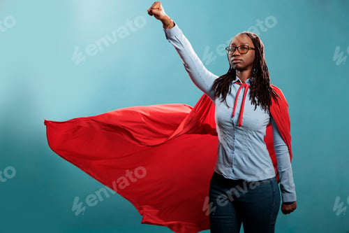 Preview: Powerful and brave young superhero woman wearing hero costume while posing as flying