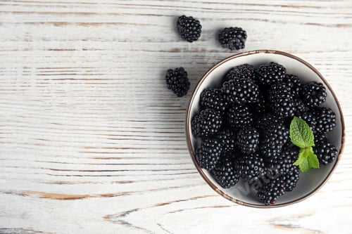 Preview: Bowl of ripe blackberries with mint on white wooden table, flat lay