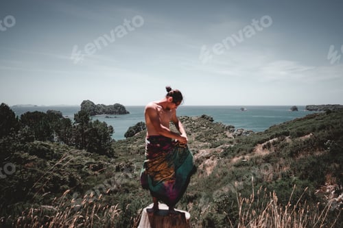 Preview: Man on stump on hill near sea