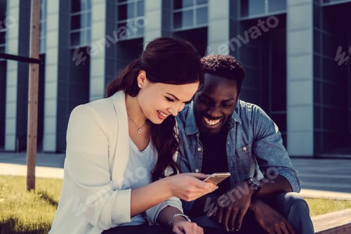 Preview: Afro american male and caucasian female with smartphone on a str