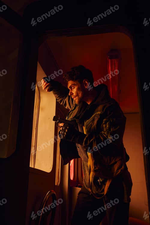Preview: man with gun standing near window of abandoned carriage in post-apocalyptic subway with red light