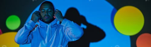 Preview: young man putting on hood with closed eyes in digital projector lights, fashion concept, banner