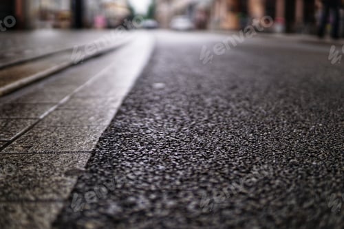 Preview: High angle shot of an asphalt road texture and a stone sidewalk