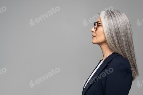 Preview: side view of beautiful asian businesswoman with grey hair in eyeglasses isolated on grey