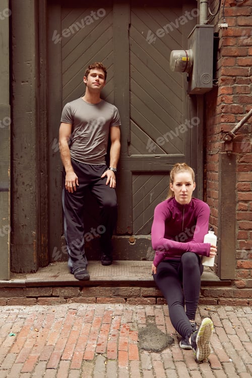 Preview: Portrait of young male and female runners in alleyway