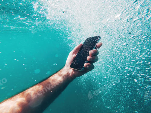 Preview: Man using smartphone device underwater in deep blue sea during summer holiday vacation