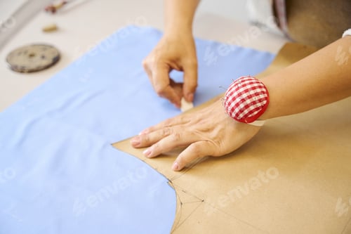 Preview: Craftswoman traces a pattern on a blue fabric with chalk