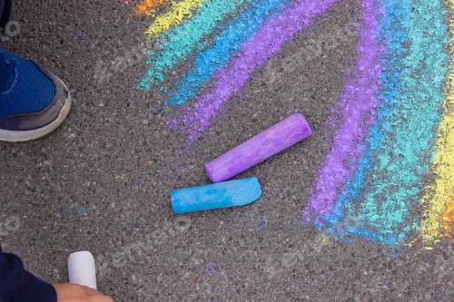 Preview: A child draws a rainbow on the asphalt. Selective focus.