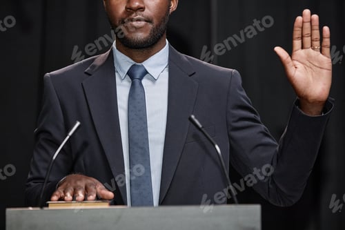 Preview: Male Politician Swearing to Obey Constitution Raising Hand while Standing at Podium Indoors