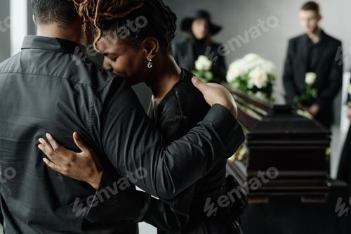 Preview: Young Black Woman Embracing Man While Mourning at Funeral Ceremony Indoors