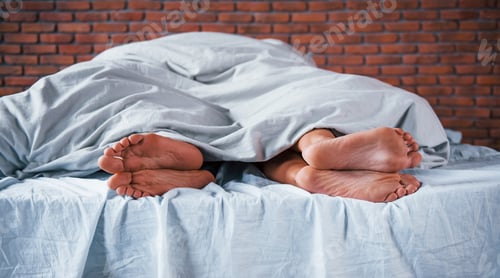 Preview: Close up view of foots of couple that sleeps together in the bedroom at morning time