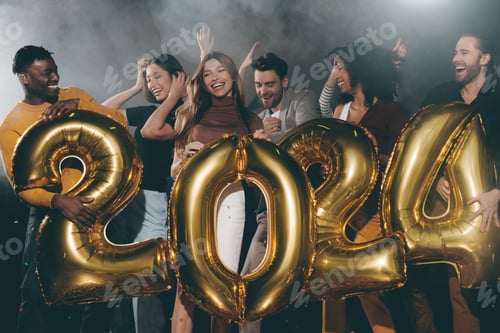 Visualização: Grupo de jovens alegres segurando balões de ouro em forma de 2024 enquanto comemoram o Ano Novo