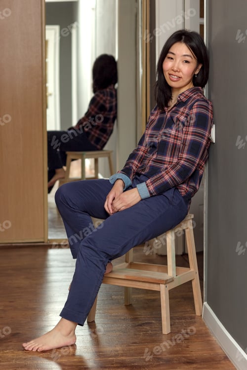 Preview: Woman in plaid shirt relaxing indoors on stool