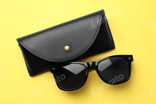 Preview: Stylish sunglasses and black leather case on yellow background, flat lay