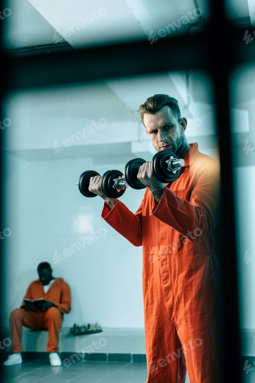 Preview: prisoner training with dumbbells in prison room behind prison bars