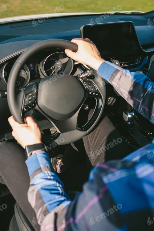 Preview: Young man holding steering wheel while driving the car