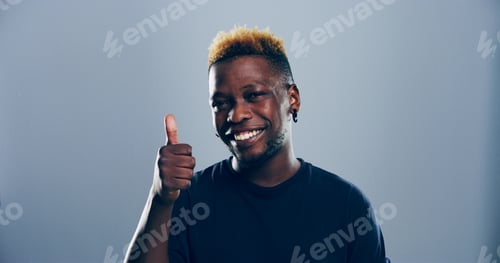 Preview: Happy, black man or portrait with thumbs up for success or positive feedback on a gray studio backg