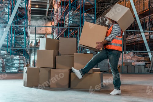 Preview: side view of bearded warehouse worker with boxes walking in storehouse
