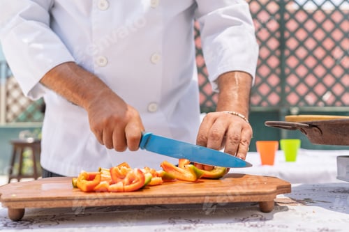 Preview: Chef slicing bell peppers outdoors for paella preparation