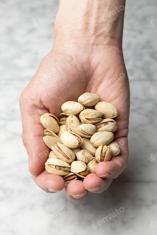 Preview: Hand holding a pile of roasted salted pistachios