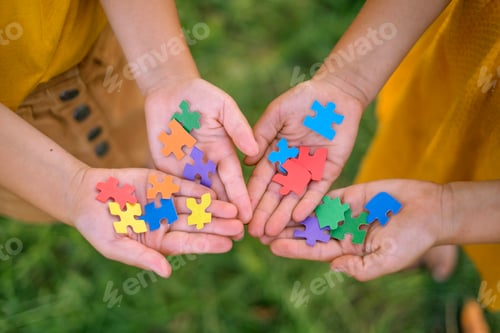Preview: Close-up of pieces of multicolored puzzles in the hands of children.