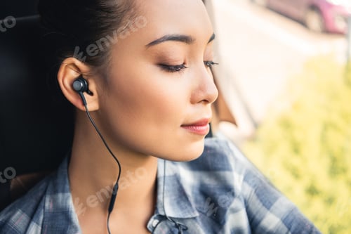 Preview: selective focus of asian female traveler listening music in earphones during trip on bus