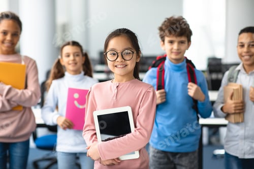 Preview: Smiling asian girl holding tablet standing with classmates