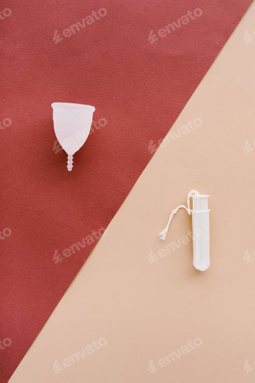 Preview: Menstrual cup and a tampon on a red and peach background