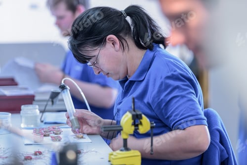 Preview: Female worker assembling electromagnets on production line in electronics factory