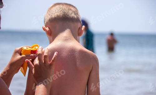 Preview: Mother puts cream on her son's back. Caring for baby skin. Sunscreens in the travel