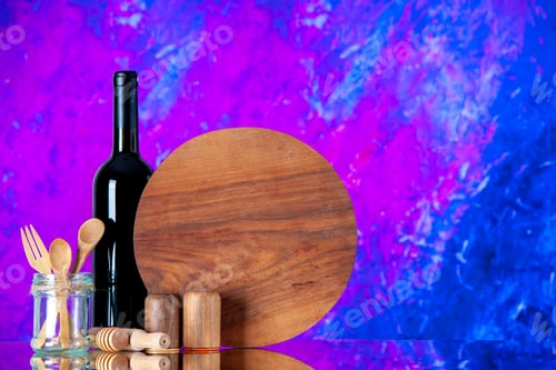 Preview: Front view of round cutting board and glass bottle wooden spoons and fork salt pepper pots on purple