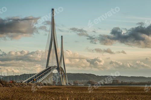 Preview: Curvy cable-stayed bridge in a grassy field under the beautiful cloudy sky