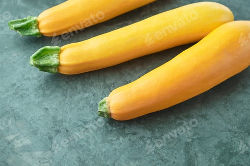 Preview: Three yellow zucchini on kitchen table. Whole raw courgettes