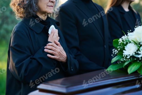 Preview: Close-up of mourning mature woman in black attire with her hands on chest