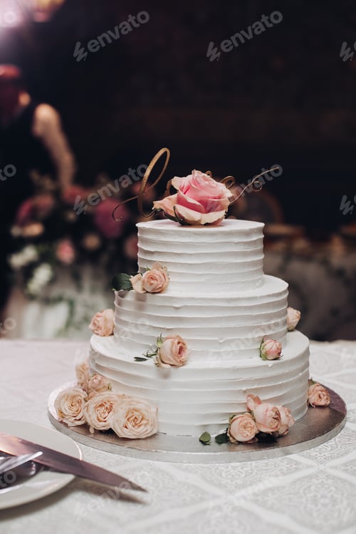 Preview: Appetizing beautiful big layered sweet wedding cake covered by white cream decorated dessert flower