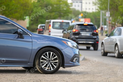 Preview: Car parked on a city street side with blurred urban traffic