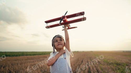 Preview: Smiling interested 5 years old child boy playing with wooden airplane, discovering future interest