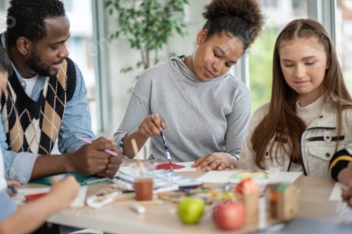 Preview: Group of students drawing and painting in Arts class with African American teacher