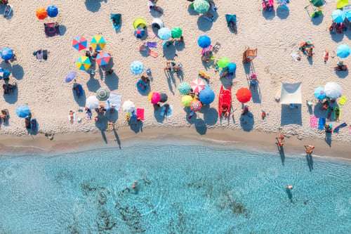 Preview: Aerial view of colorful umbrellas on sandy beach, swimming people in blue sea at sunset