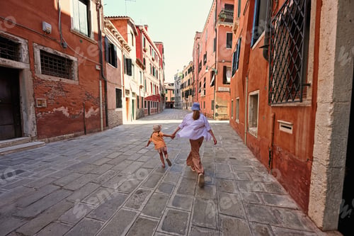 Preview: Back of sisters holding hands and run in street Venice, Italy.