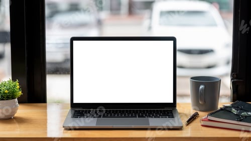 Preview: Image of a laptop blank white screen on a desk near a window at the office with a coffee mug.